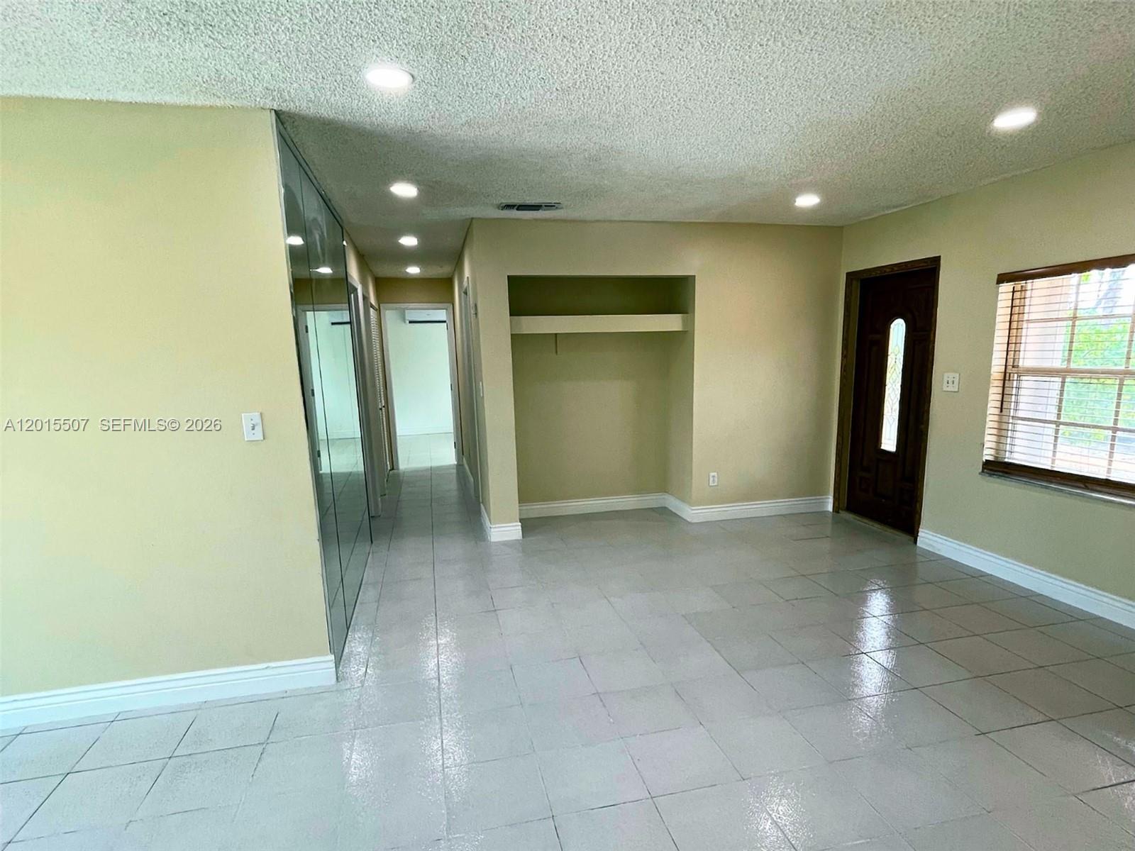 A room with light-colored tile flooring, a recessed wall niche, and a dark wood door — 22430 SW 113th Ct, Miami FL 33170, MIAMI, FL