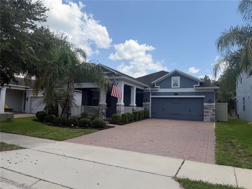 An open-concept living room with dark wood-look tile floors flows into a modern white kitchen — 1211 TURNBRIDGE PLACE, OVIEDO, FL
