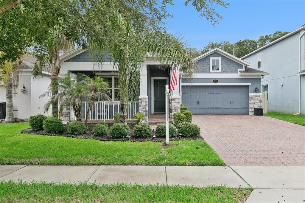 A living room features a white stone fireplace, built-in shelving, dark wood floors, and shutters — 1211 TURNBRIDGE PLACE, OVIEDO, FL