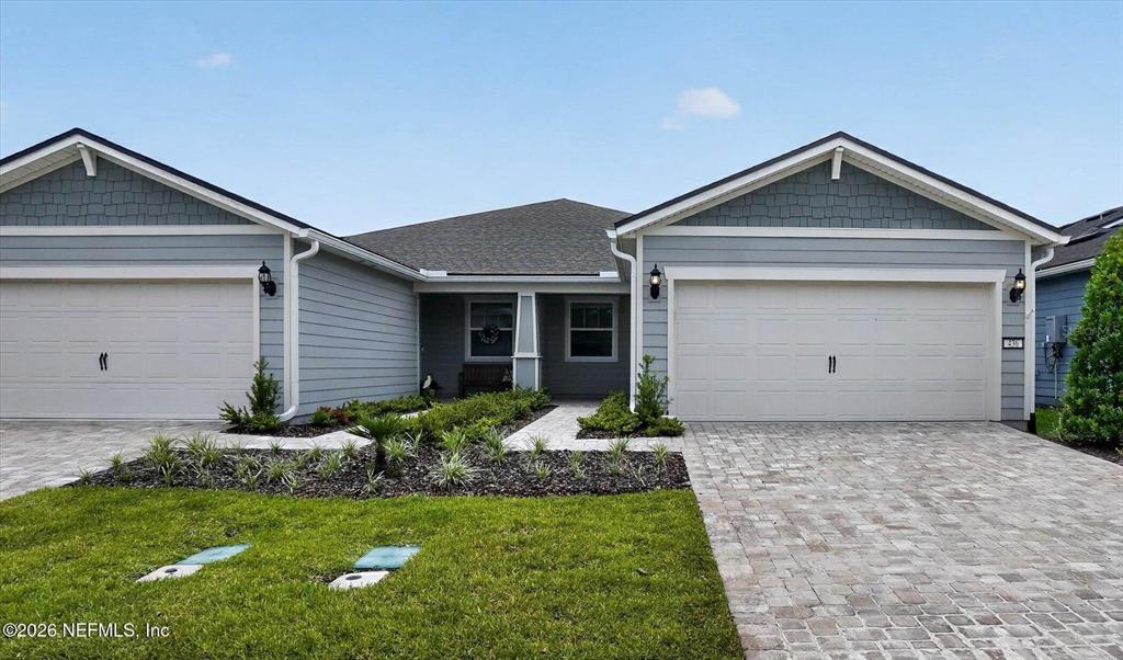 A light blue house features two garage doors, a paved driveway, and a landscaped front yard — 436 JUBILEE CIRCLE, YULEE, FL
