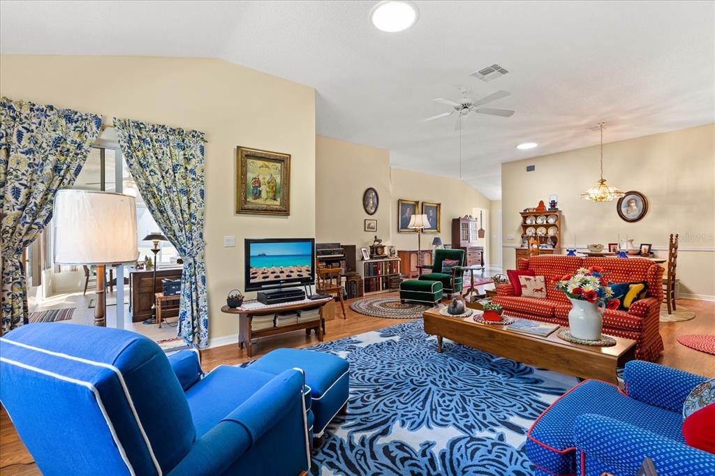 A living room features a blue patterned rug, a red sofa, and blue armchairs — 1301 FONTANA COURT, THE VILLAGES, FL