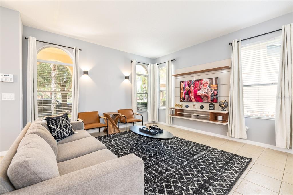 A living room features a grey sofa, a black coffee table, and a wall-mounted television — 161 LAS FUENTES DRIVE, KISSIMMEE, FL