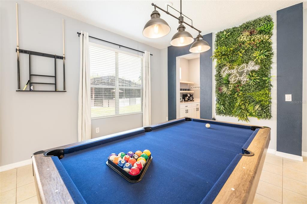 A game room features a blue pool table, a neon sign, and a vertical garden wall — 161 LAS FUENTES DRIVE, KISSIMMEE, FL