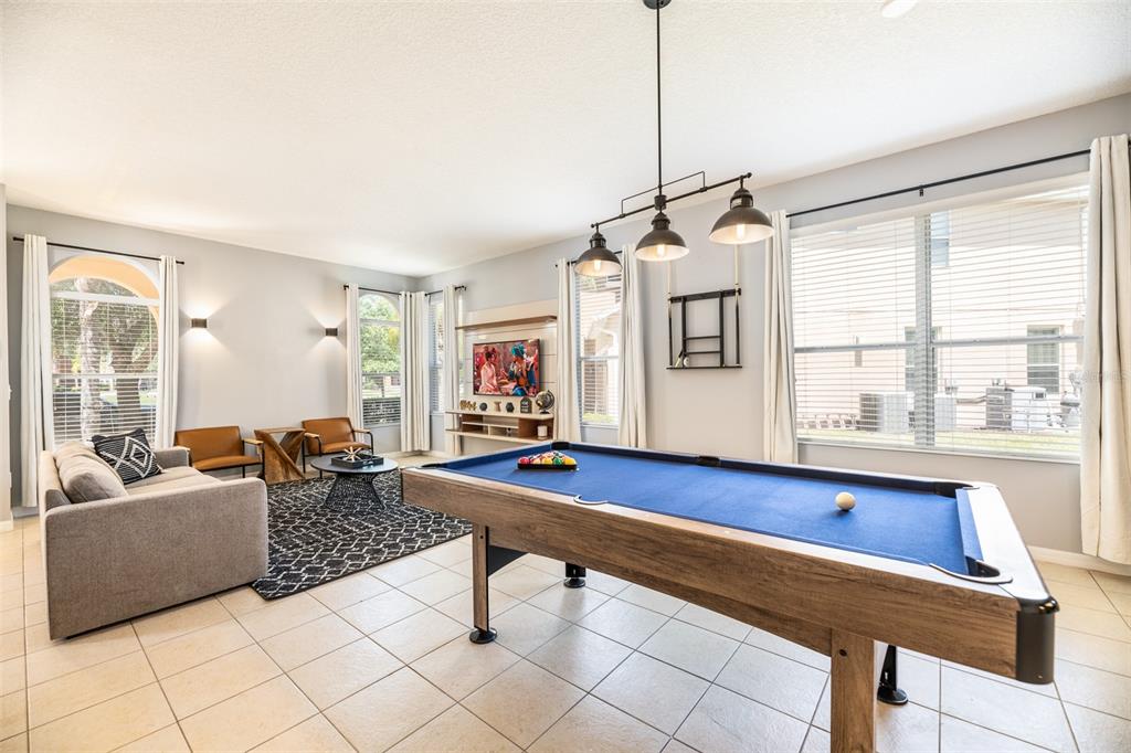 A game room features a pool table, a gray sofa, and large windows with curtains — 161 LAS FUENTES DRIVE, KISSIMMEE, FL