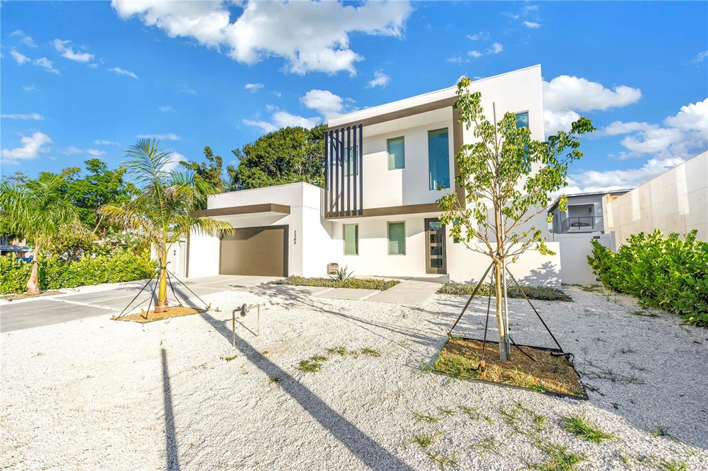 A modern two-story white house features a garage, gravel yard, and young trees — 2305 TEMPLE STREET, SARASOTA, FL