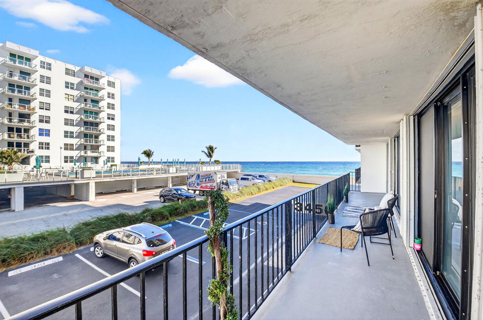 A balcony with a black metal railing overlooks a parking lot and the ocean — 3456 S Ocean Boulevard # 1040, Palm Beach FL 33480, PALM BEACH, FL