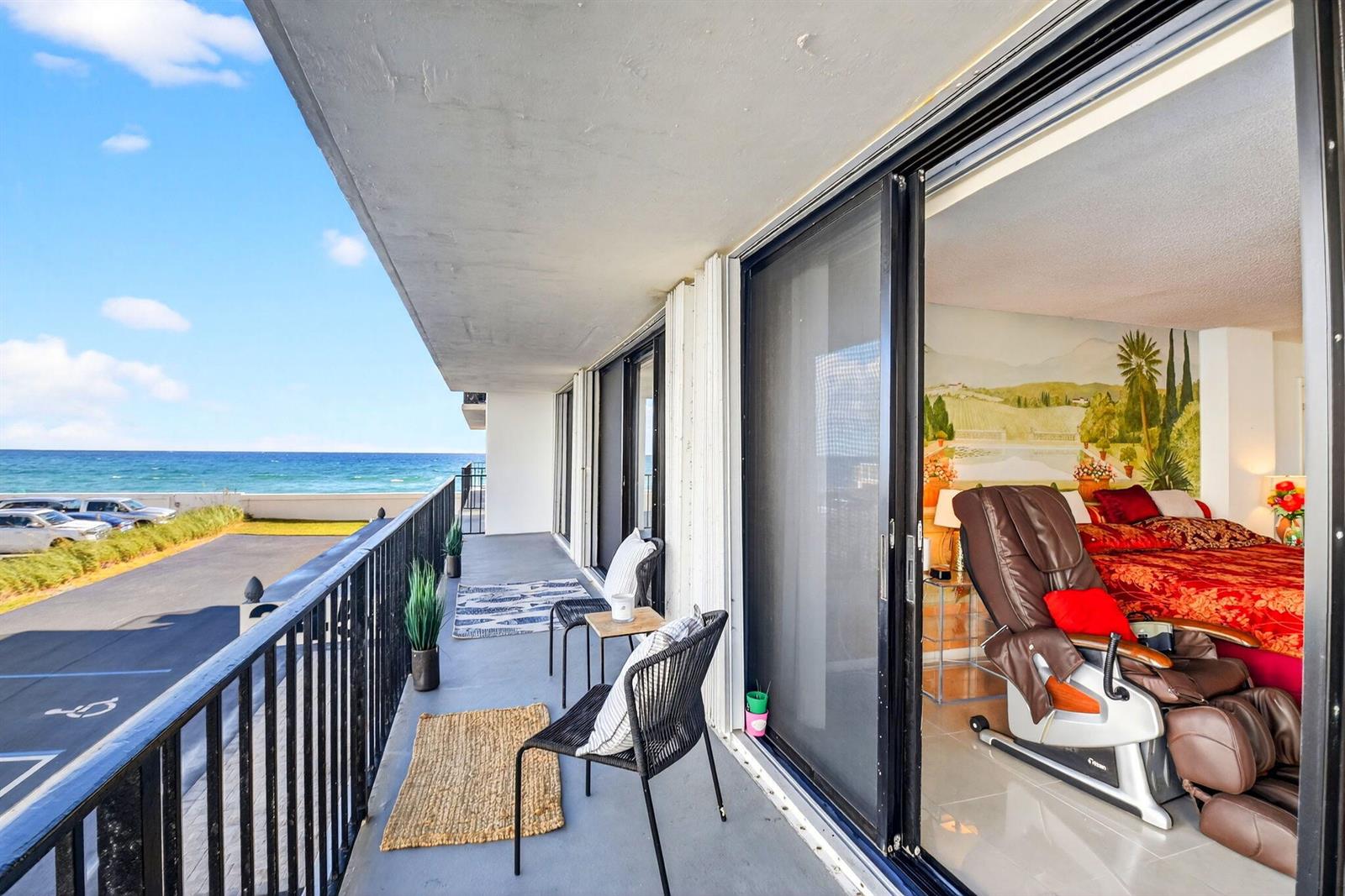 A balcony with outdoor seating overlooks the ocean next to a bedroom with a massage chair — 3456 S Ocean Boulevard # 1040, Palm Beach FL 33480, PALM BEACH, FL