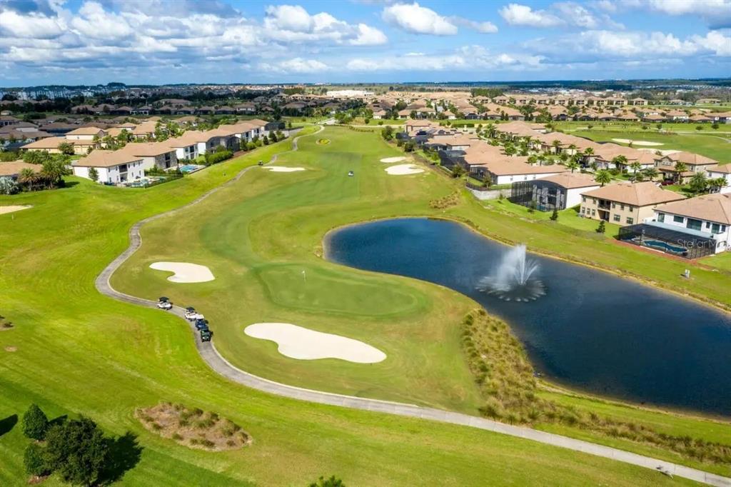 An aerial view of a golf course fairway with a pond, fountain, and surrounding houses — 8836 CRUDEN BAY COURT, DAVENPORT, FL