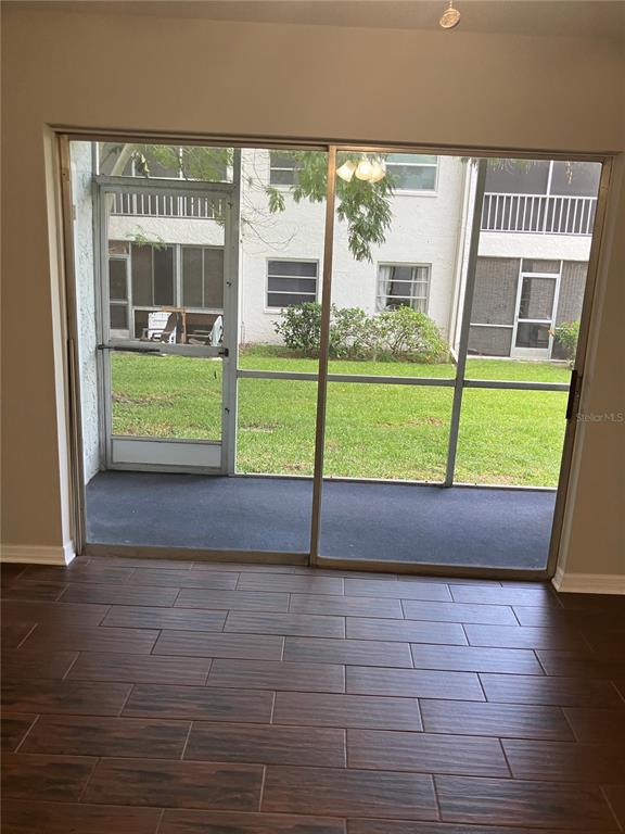A room with dark wood-look tile flooring looking out through a sliding door to a patio — 337 S MCMULLEN BOOTH ROAD UNIT 157, CLEARWATER, FL