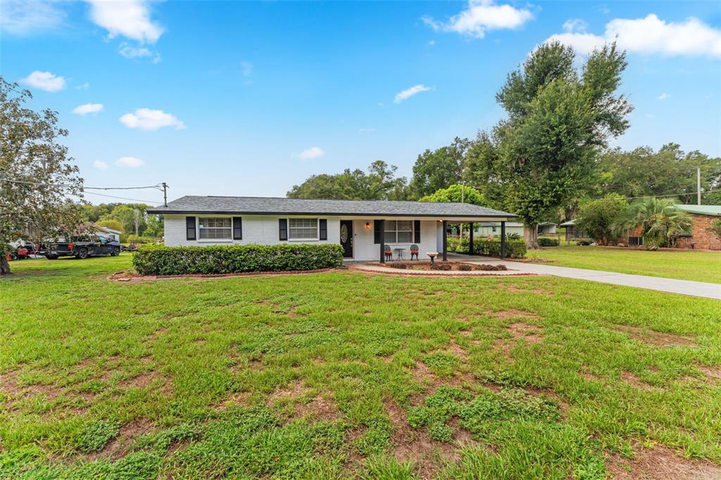 A single-story white house with a black roof and a front carport sits on grass — 3825 SWINDELL ROAD, PLANT CITY, FL