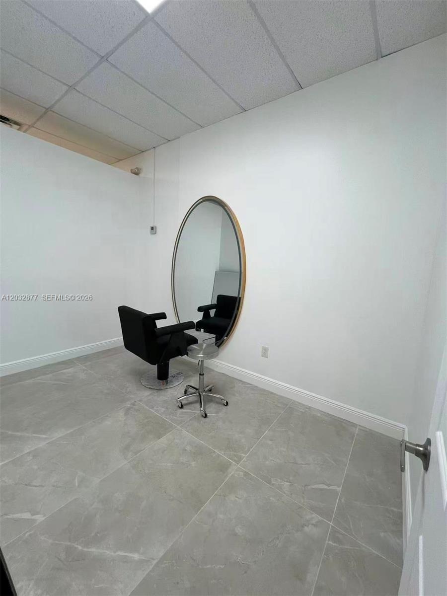 A salon room features a large oval mirror, a black styling chair, and tiled flooring — Stirling Rd, Davie FL 33314, DAVIE, FL