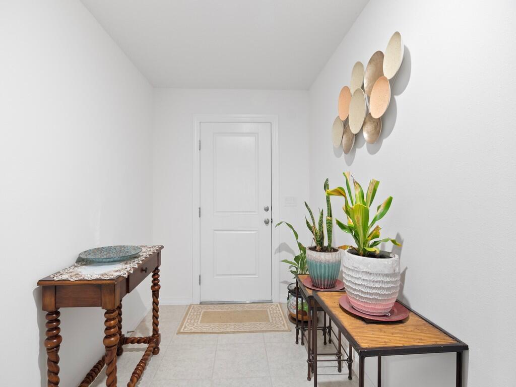 A bright entryway features a white door, tiled floors, and two wooden console tables — 7976 105th Avenue, Vero Beach FL 32967, VERO BEACH, FL