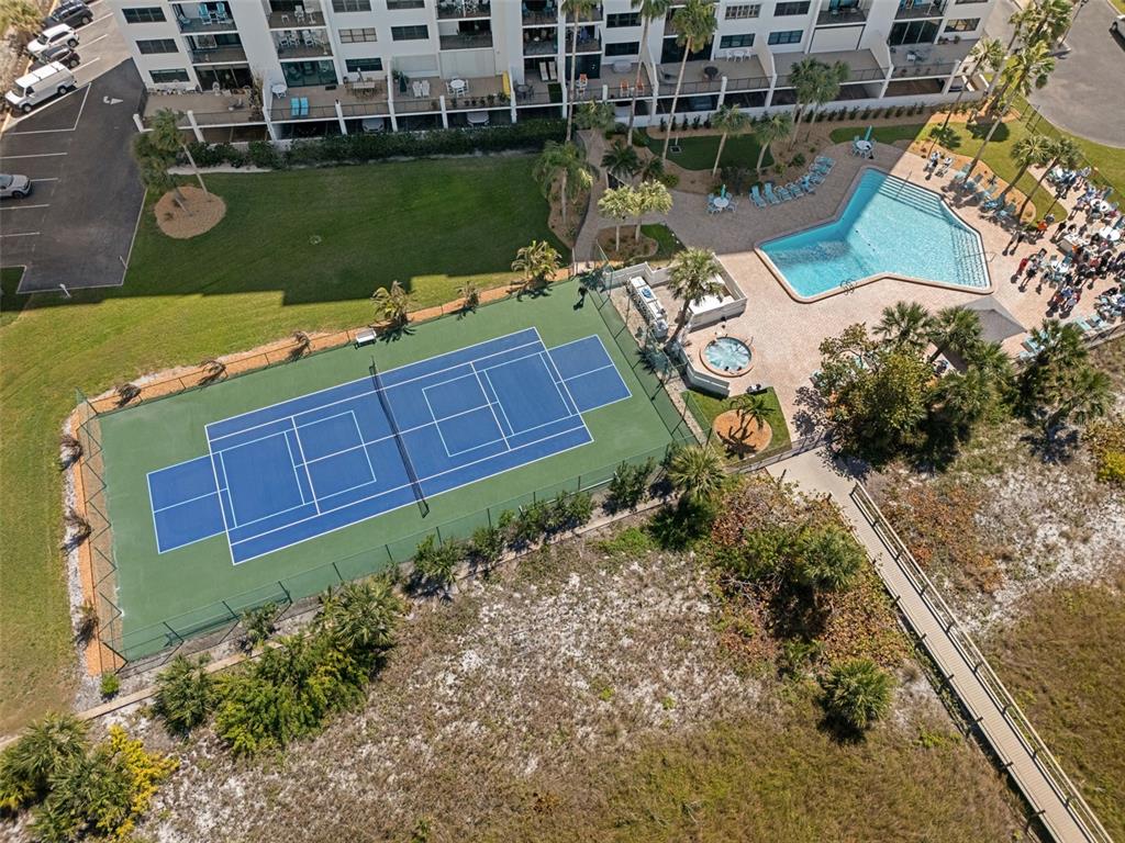 An aerial view shows a tennis court, swimming pool, hot tub, and a wooden boardwalk — 1230 GULF BOULEVARD UNIT 303, CLEARWATER BEACH, FL