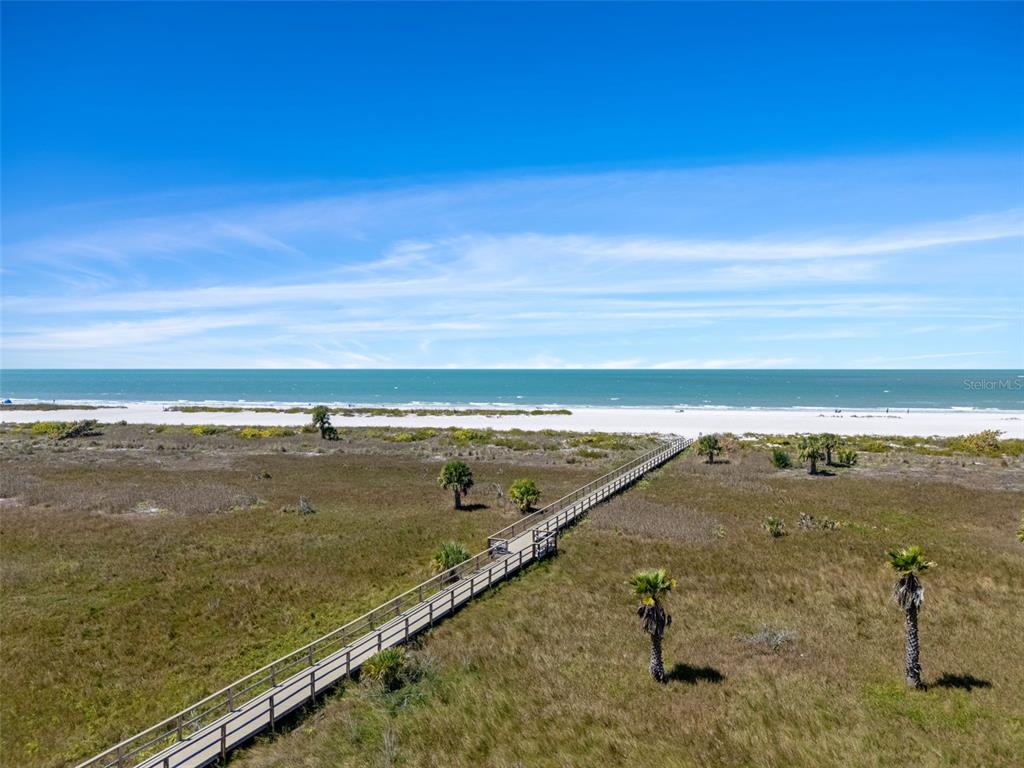An elevated wooden boardwalk leads through grassy dunes toward a sandy beach and ocean — 1230 GULF BOULEVARD UNIT 303, CLEARWATER BEACH, FL