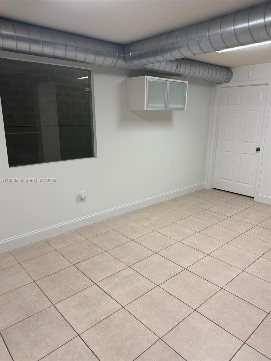 This room features tiled floors, white walls, a window, a wall cabinet, and exposed ductwork — 4616 NW 133rd St # 4616, Opa-Locka FL 33054, OPA-LOCKA, FL