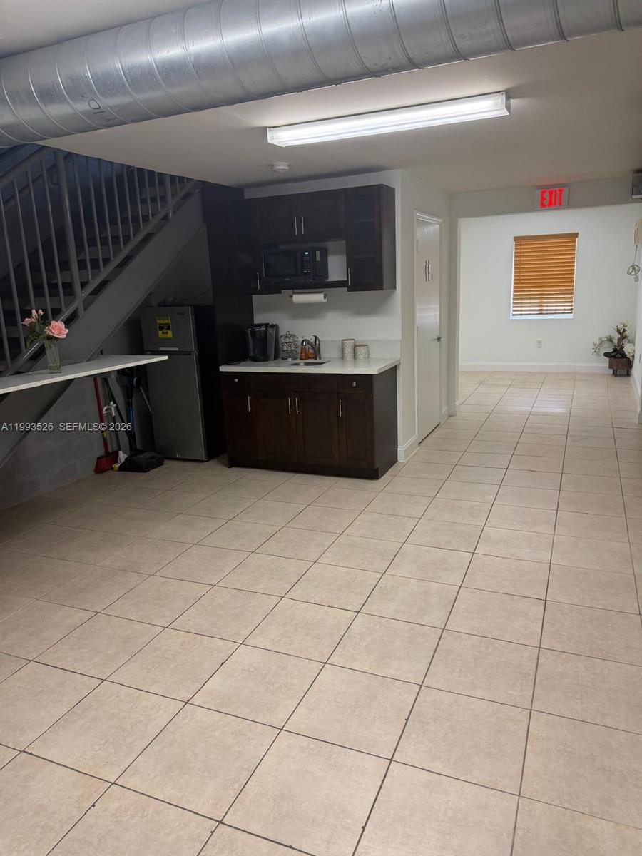 A kitchenette with dark cabinets sits beneath a staircase in a tiled office space — 4616 NW 133rd St # 4616, Opa-Locka FL 33054, OPA-LOCKA, FL