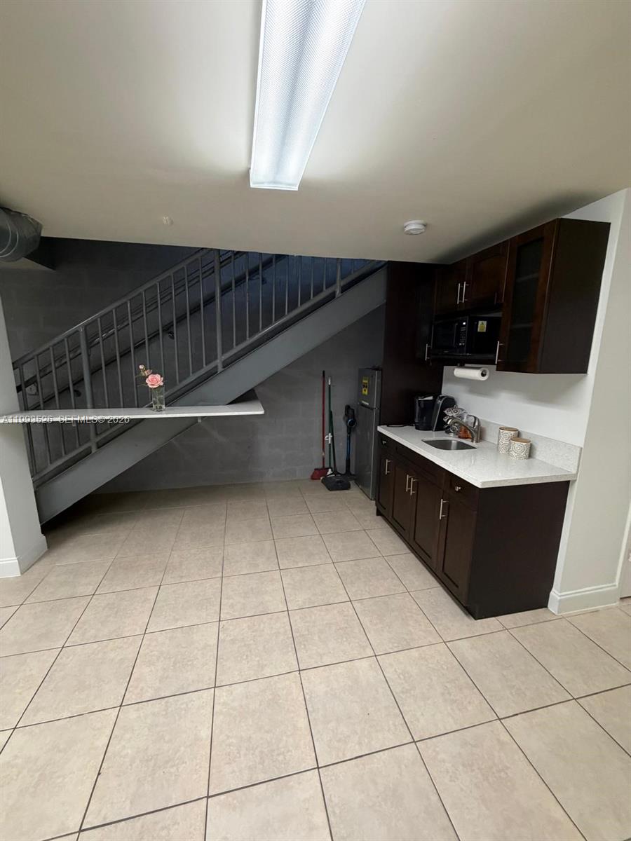 A kitchenette with dark cabinets and a sink is positioned under a metal staircase — 4616 NW 133rd St # 4616, Opa-Locka FL 33054, OPA-LOCKA, FL