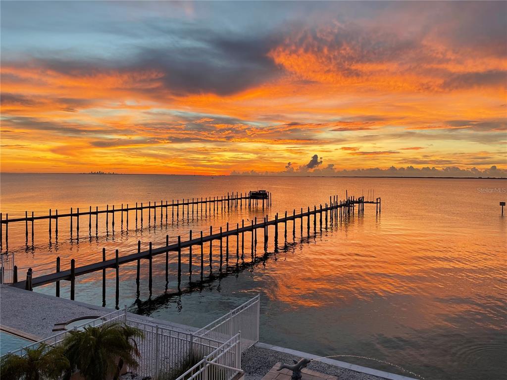 A long wooden pier extends into the water during a vibrant orange sunset — 6418 BRIGHT BAY COURT, APOLLO BEACH, FL