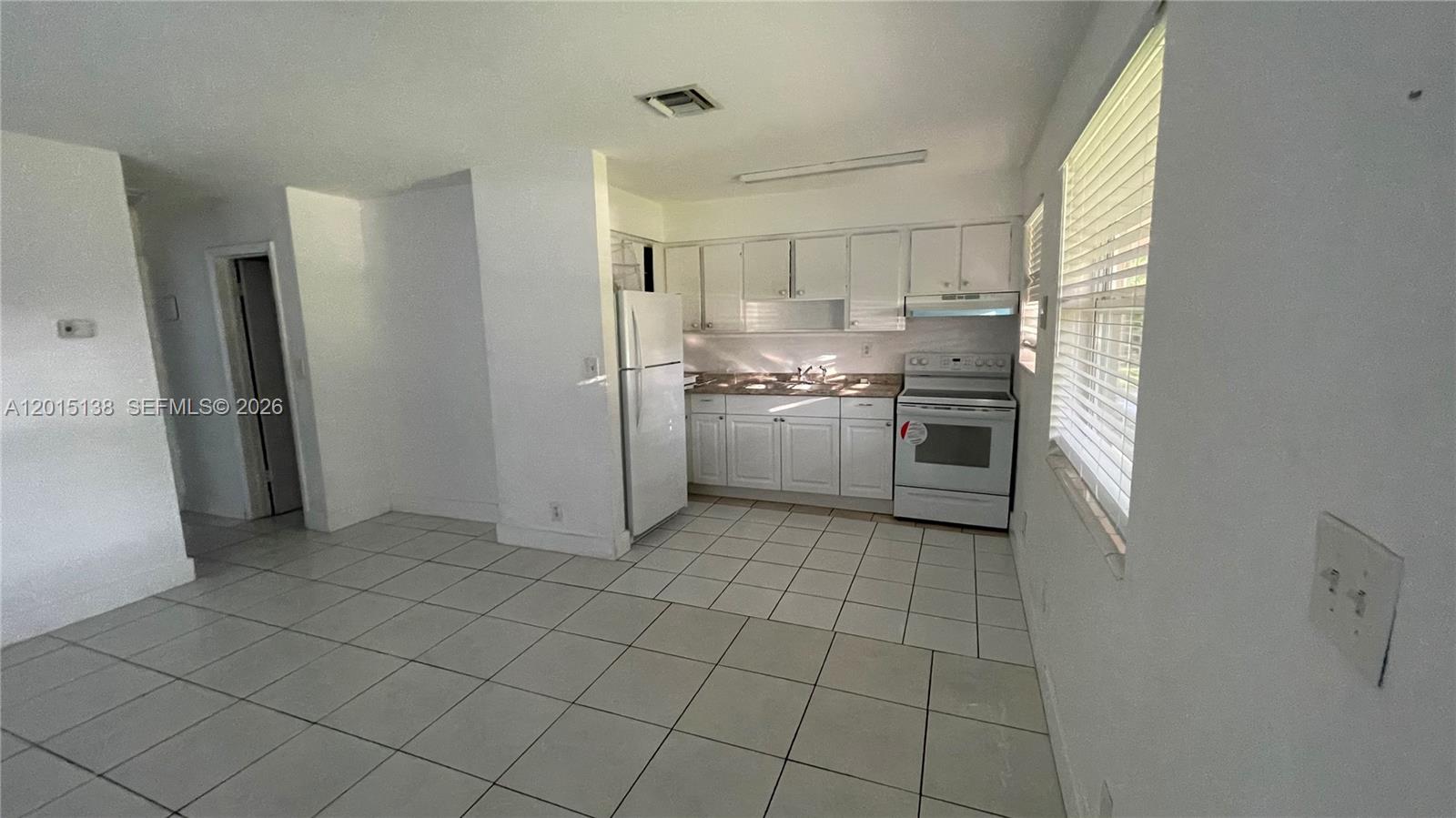 A kitchen features white cabinets, white appliances, and light-colored tile flooring — 5200 NW 16th St, Lauderhill FL 33313, LAUDERHILL, FL