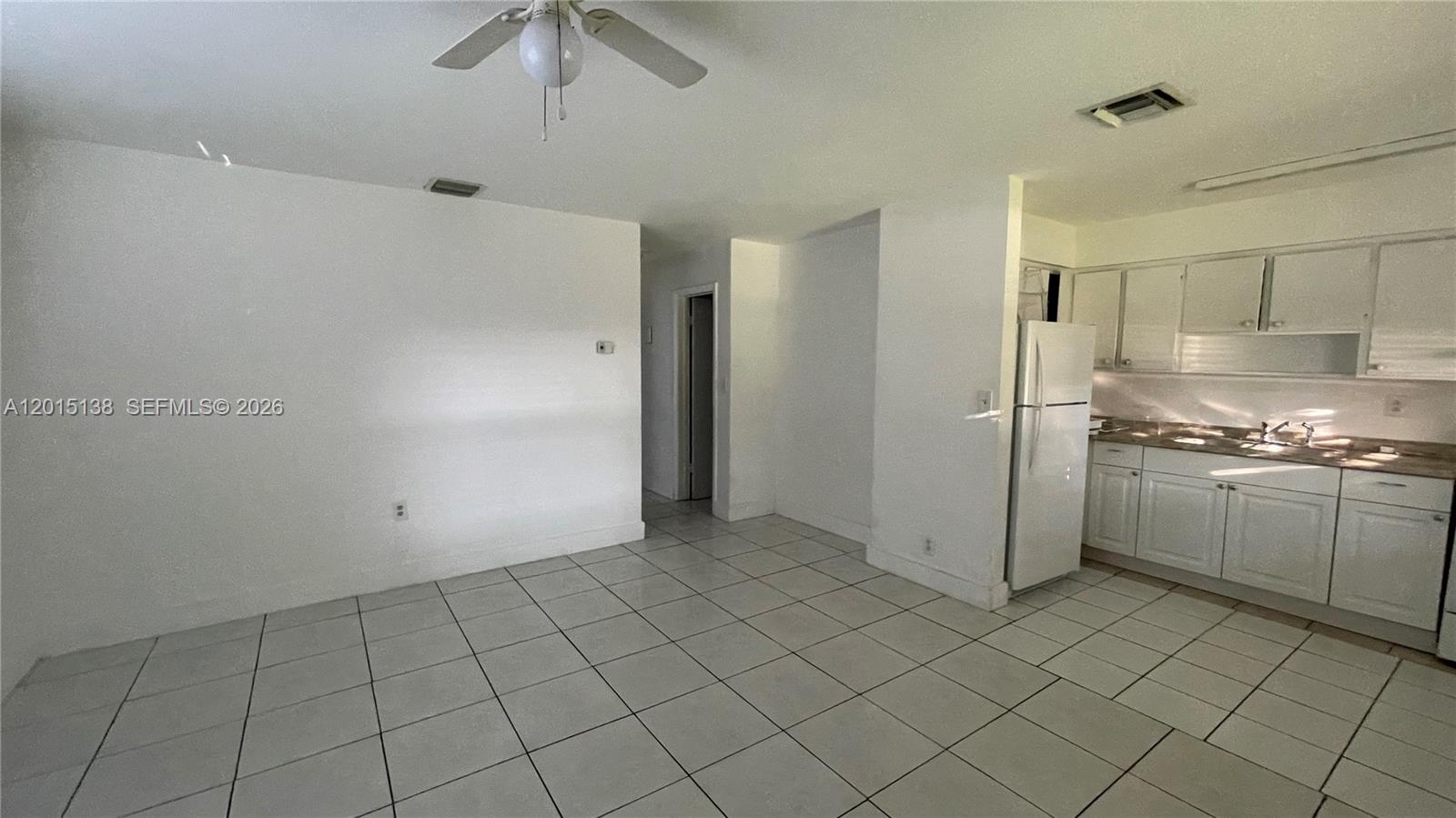 An open-concept room features white walls, tiled floors, a ceiling fan, and a kitchen area — 5200 NW 16th St, Lauderhill FL 33313, LAUDERHILL, FL
