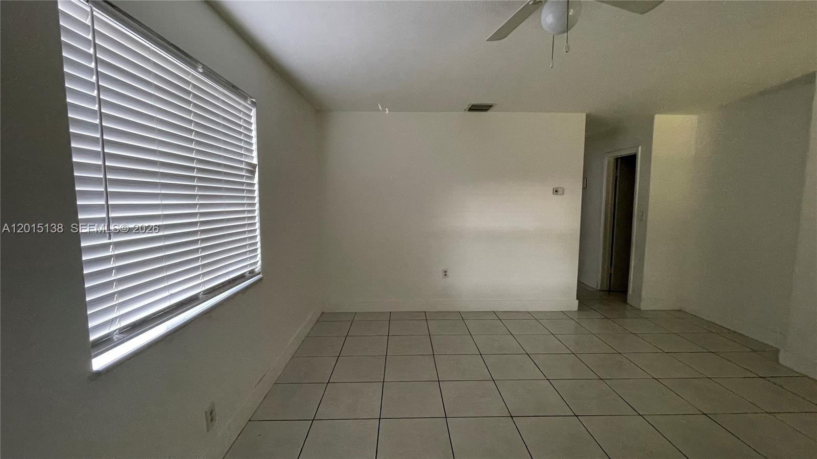 An empty room features white walls, light-colored floor tiles, a window with blinds, and a ceiling fan — 5200 NW 16th St, Lauderhill FL 33313, LAUDERHILL, FL