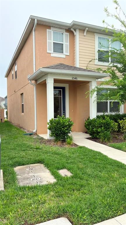 A two-story house with tan stucco and siding, a covered front porch, and a small lawn — 11546 BUOY POINT PLACE, ORLANDO, FL