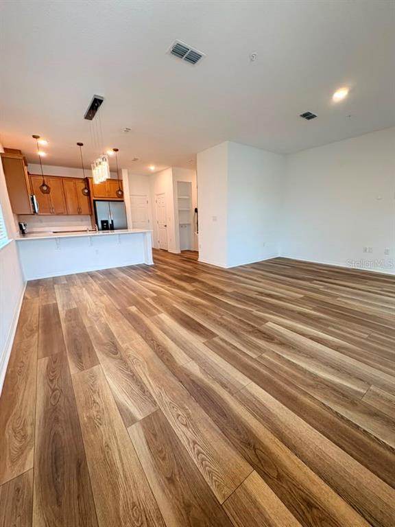 An open-concept kitchen with wood-look flooring and a breakfast bar overlooks a living area — 11546 BUOY POINT PLACE, ORLANDO, FL