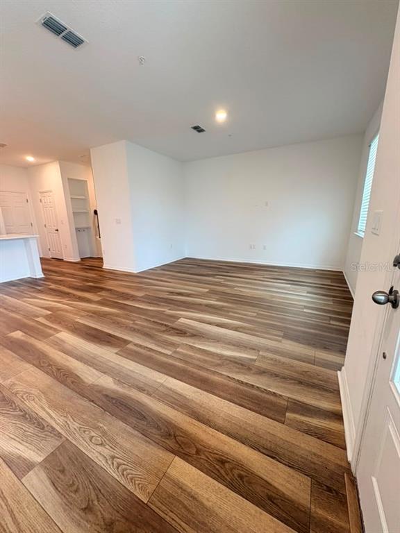 An open-concept living area features wood-look flooring, white walls, and a recessed storage nook — 11546 BUOY POINT PLACE, ORLANDO, FL