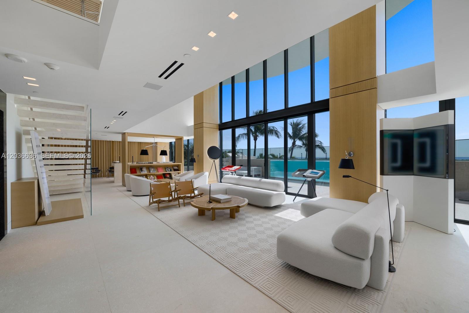 A modern, high-ceilinged living room features white sofas, a wooden coffee table, and floor-to-ceiling windows — 19575 Collins Ave # 3, Sunny Isles Beach FL 33160, SUNNY ISLES BEACH, FL