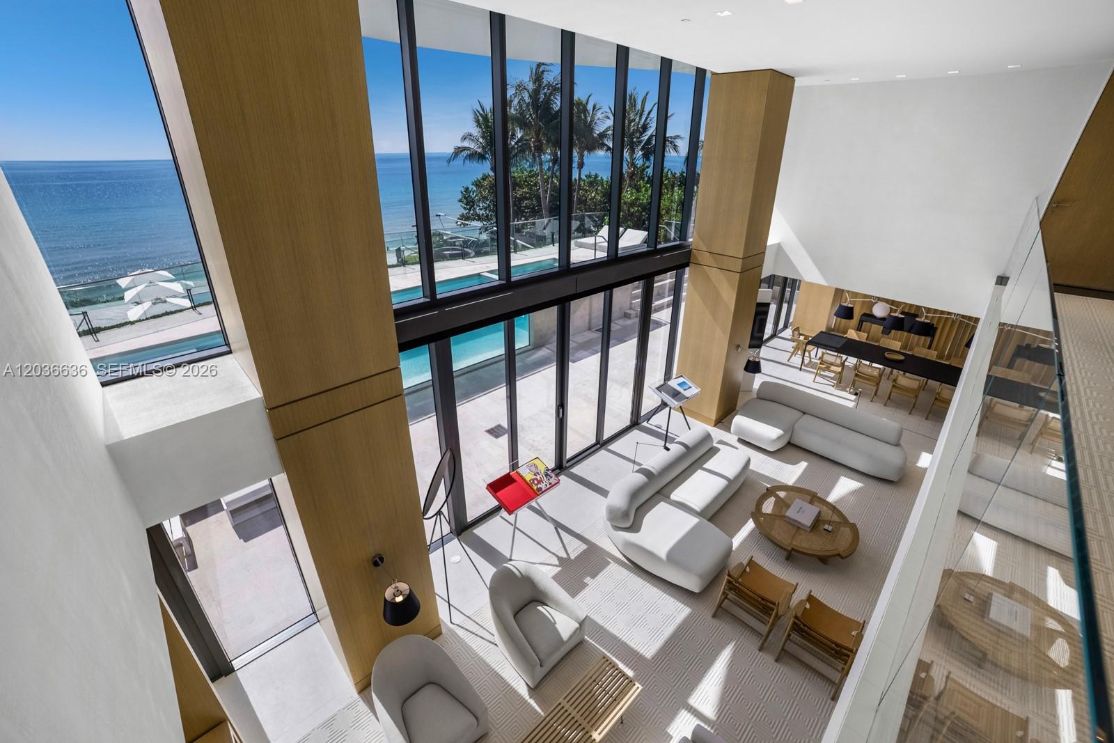 A high-ceilinged living room features floor-to-ceiling windows overlooking a swimming pool and the ocean — 19575 Collins Ave # 3, Sunny Isles Beach FL 33160, SUNNY ISLES BEACH, FL
