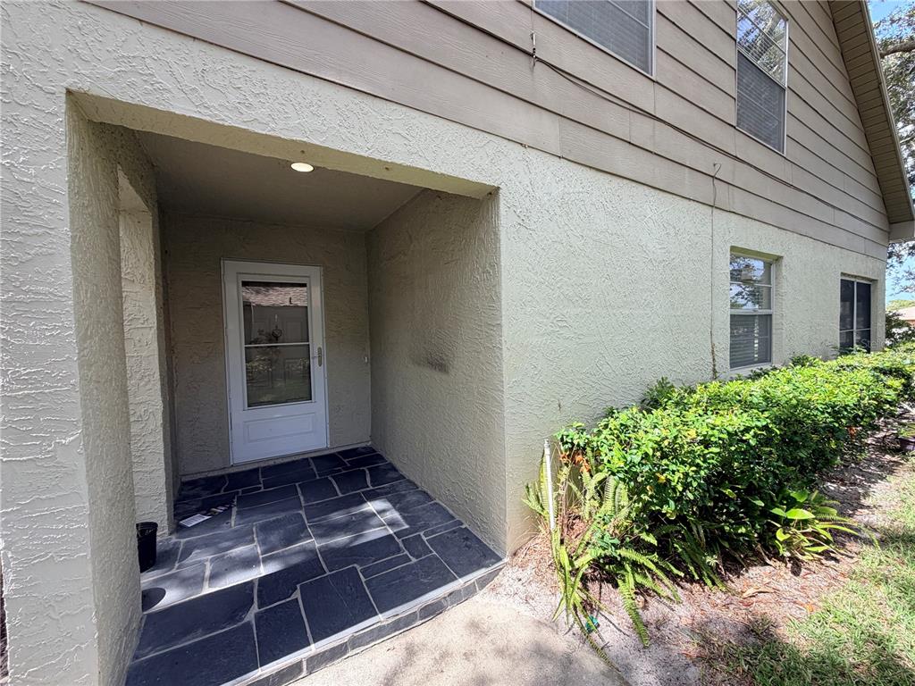 A covered entryway features a dark stone-tiled floor and a white storm door — 3417 ROCHELLE COURT, CLEARWATER, FL