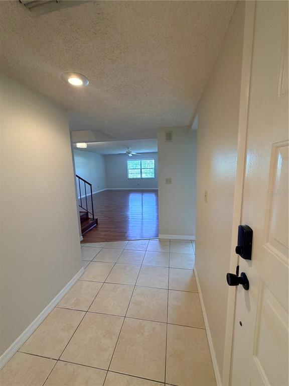 An entryway with tiled flooring leads into a living area with wood-look floors and stairs — 3417 ROCHELLE COURT, CLEARWATER, FL