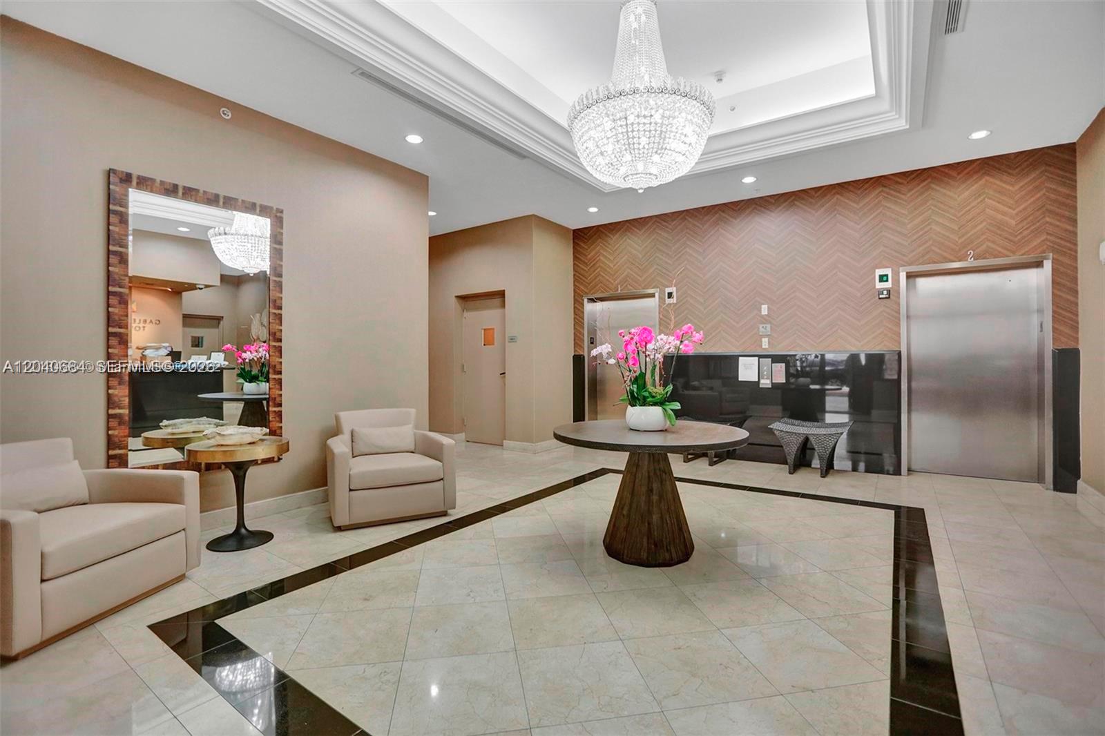 A lobby features a crystal chandelier, a round table with flowers, and two elevators — 357 Almeria Ave # 703, Coral Gables FL 33134, CORAL GABLES, FL
