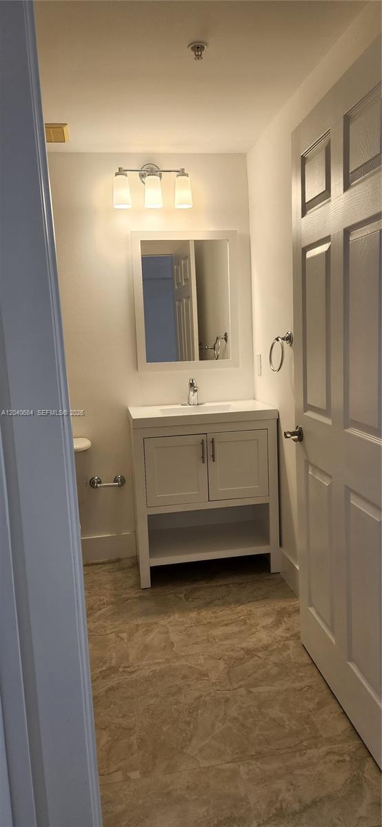 A small bathroom features a white vanity, a mirror, and light-colored tile flooring — 357 Almeria Ave # 703, Coral Gables FL 33134, CORAL GABLES, FL