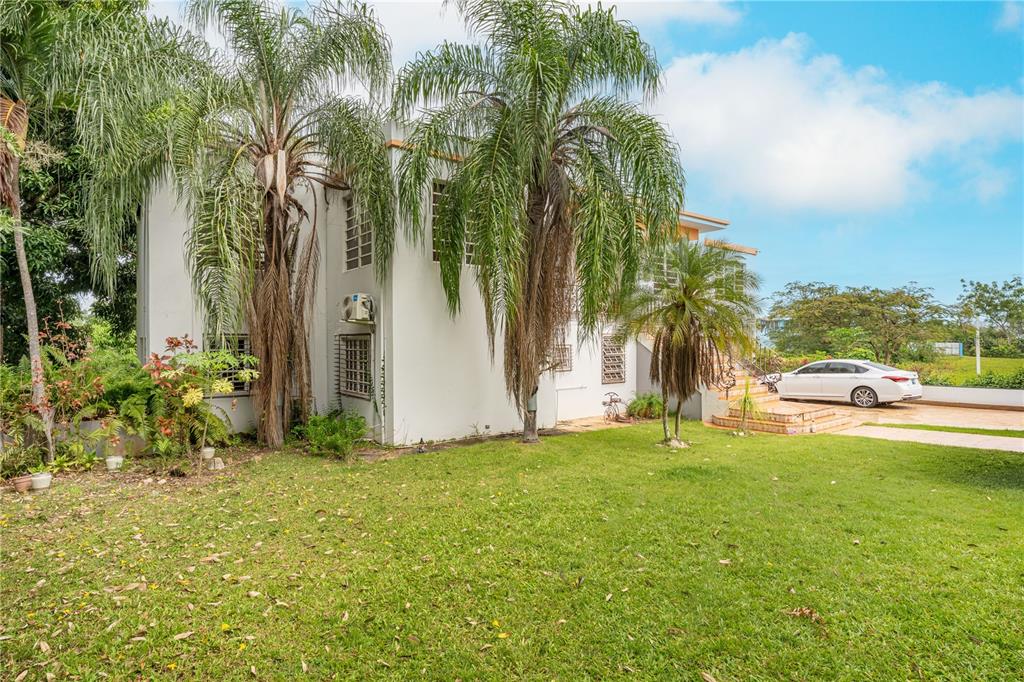 A two-story house with palm trees, a grassy lawn, and a parked white sedan — SR 100 k2h7 int Guanajibo PLAN BONITO ST, CABO ROJO, PR