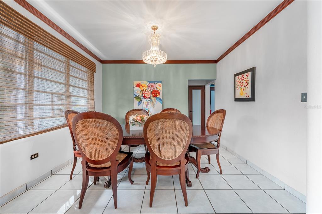 A dining room features a wooden table, cane-back chairs, a crystal chandelier, and tiled floors — SR 100 k2h7 int Guanajibo PLAN BONITO ST, CABO ROJO, PR