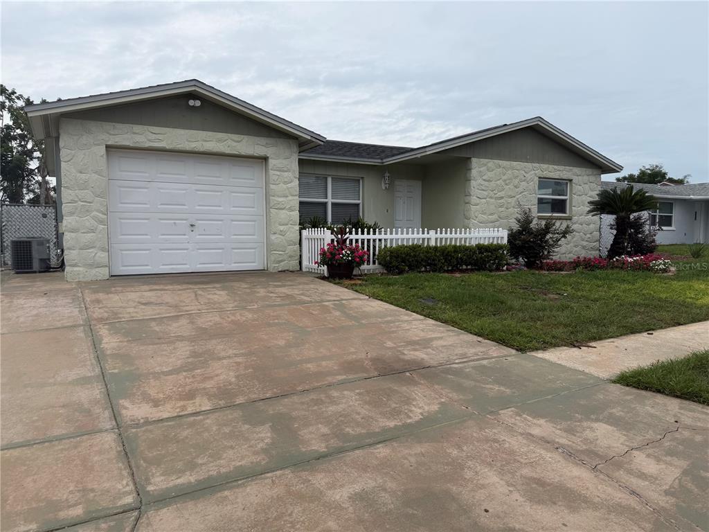 A single-story house features a white garage door, stone facade, and a small front yard — 6310 DIAMOND DRIVE DRIVE, NEW PORT RICHEY, FL