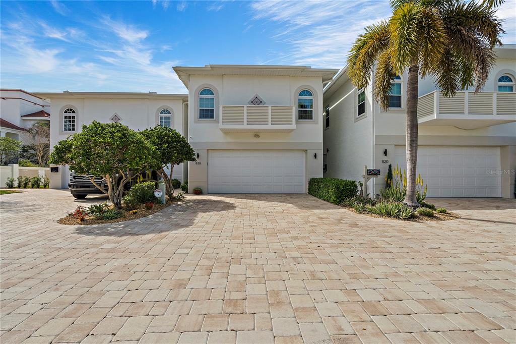 The exterior of a multi-story residential building features a paved driveway and a palm tree — 830 PINELLAS BAYWAY S, TIERRA VERDE, FL