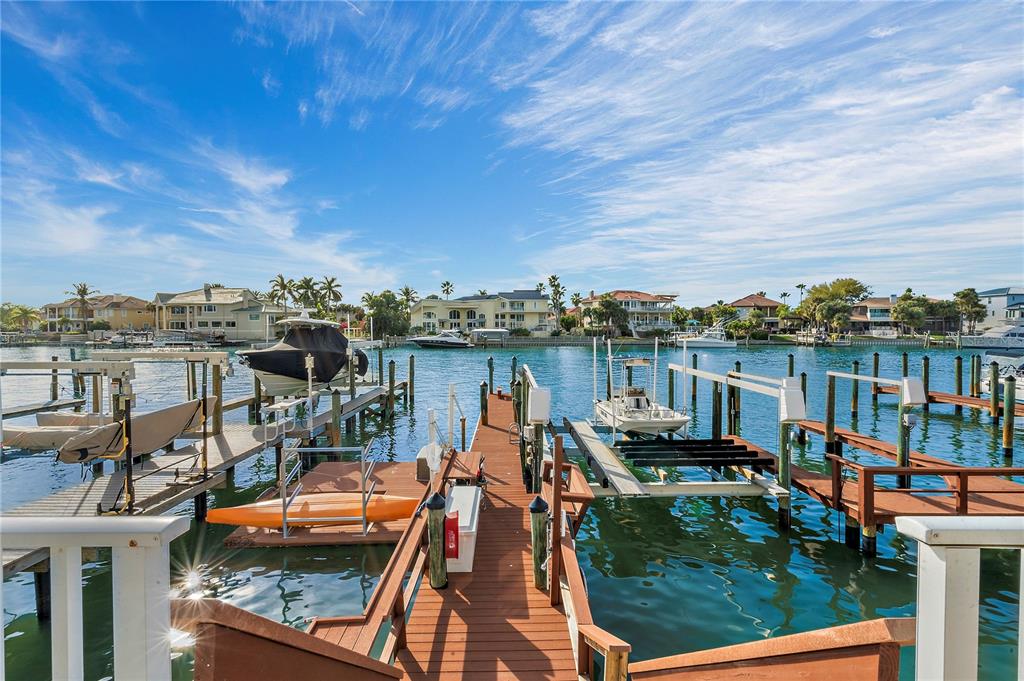 A wooden boat dock extends into a canal lined with houses and moored boats — 830 PINELLAS BAYWAY S, TIERRA VERDE, FL