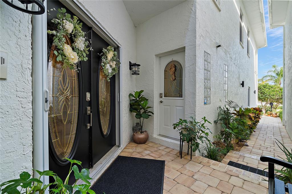 A white stucco exterior features a black double front door and a side entrance door — 830 PINELLAS BAYWAY S, TIERRA VERDE, FL
