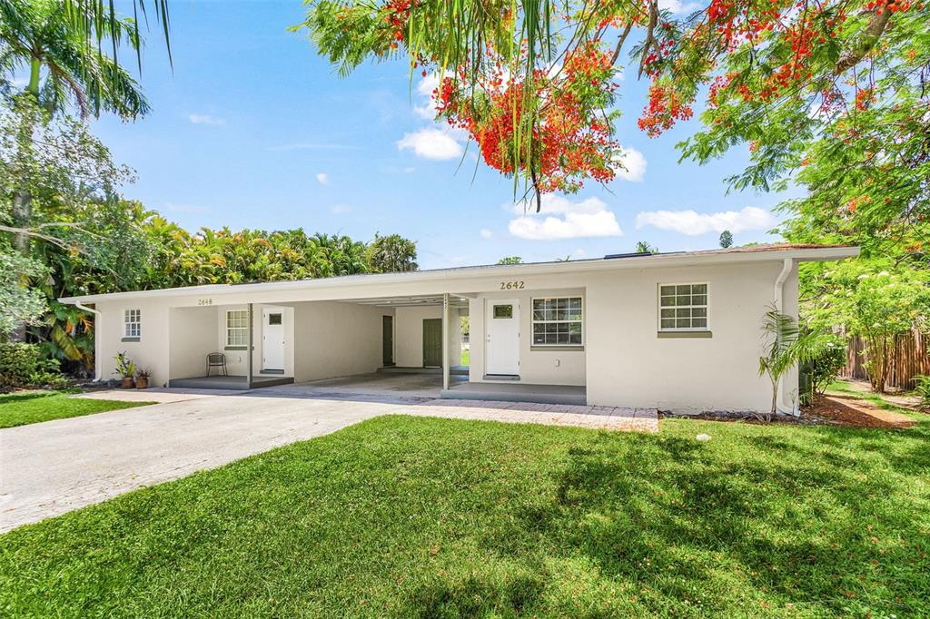 A single-story duplex with a shared carport, white exterior walls, and a grassy front yard — 2648 MICHIGAN AVENUE, FORT MYERS, FL
