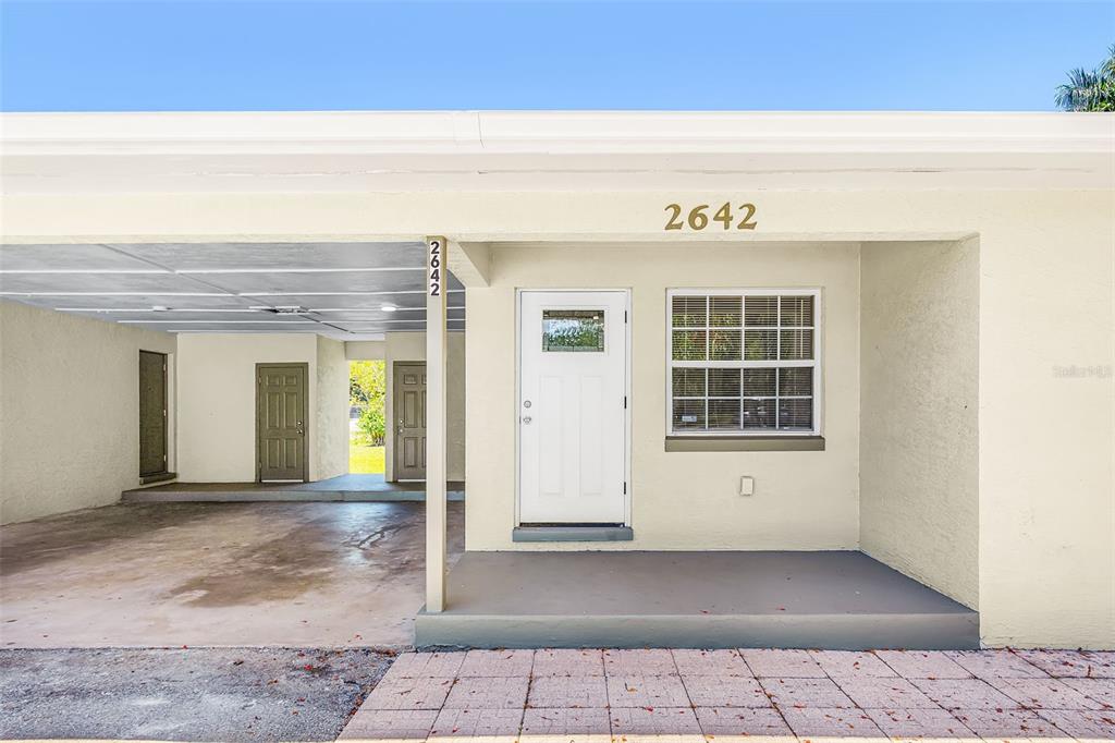 The exterior of a single-story home features a carport, a white front door, and windows — 2648 MICHIGAN AVENUE, FORT MYERS, FL