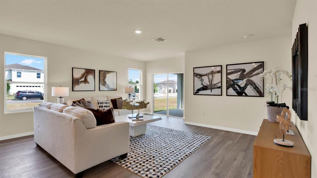 A living room features a beige sofa, a patterned rug, and sliding glass doors — 4415 BLACKWELL AVENUE, LAKE WALES, FL