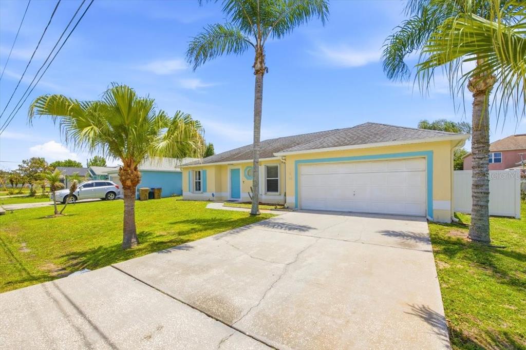 A yellow single-story house with a two-car garage and palm trees in the front yard — 182 BIRMINGHAM DRIVE, KISSIMMEE, FL