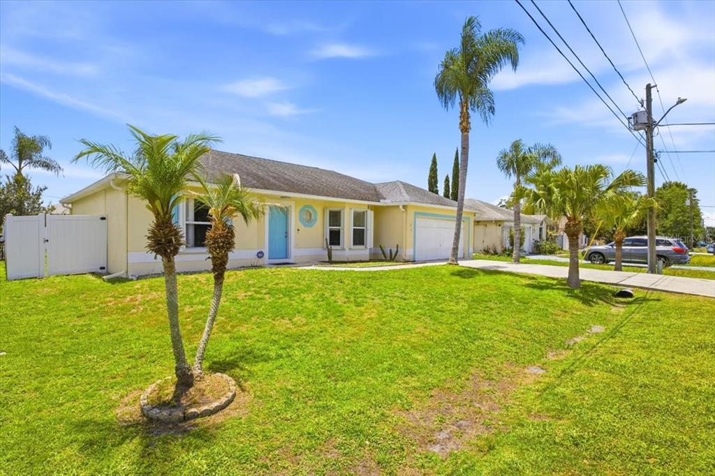 A yellow single-story house with a blue front door and palm trees in the yard — 182 BIRMINGHAM DRIVE, KISSIMMEE, FL