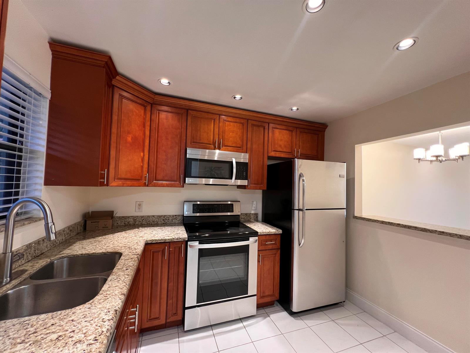 A kitchen features cherry wood cabinets, granite countertops, stainless steel appliances, and white tile flooring — 21911 Lake Forest Circle # 206, Boca Raton FL 33433, BOCA RATON, FL