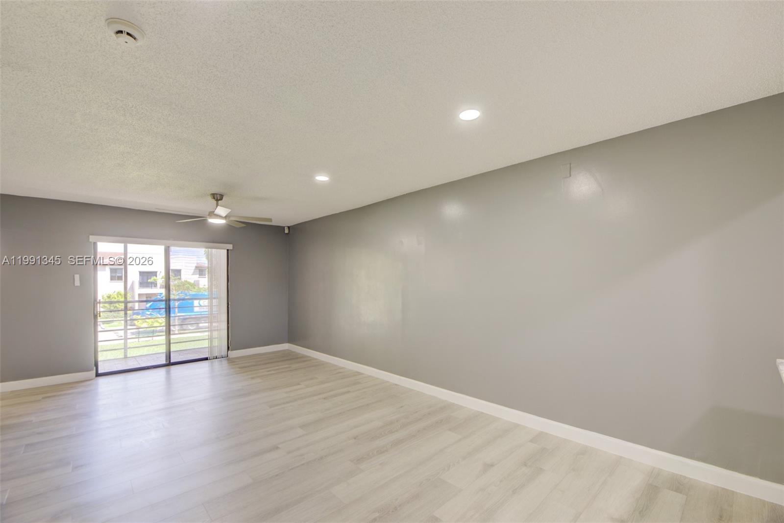 A spacious living room features light wood-look flooring, gray walls, recessed lighting, and a ceiling fan — 851 NE 209th Ter # 23, Miami FL 33179, MIAMI, FL