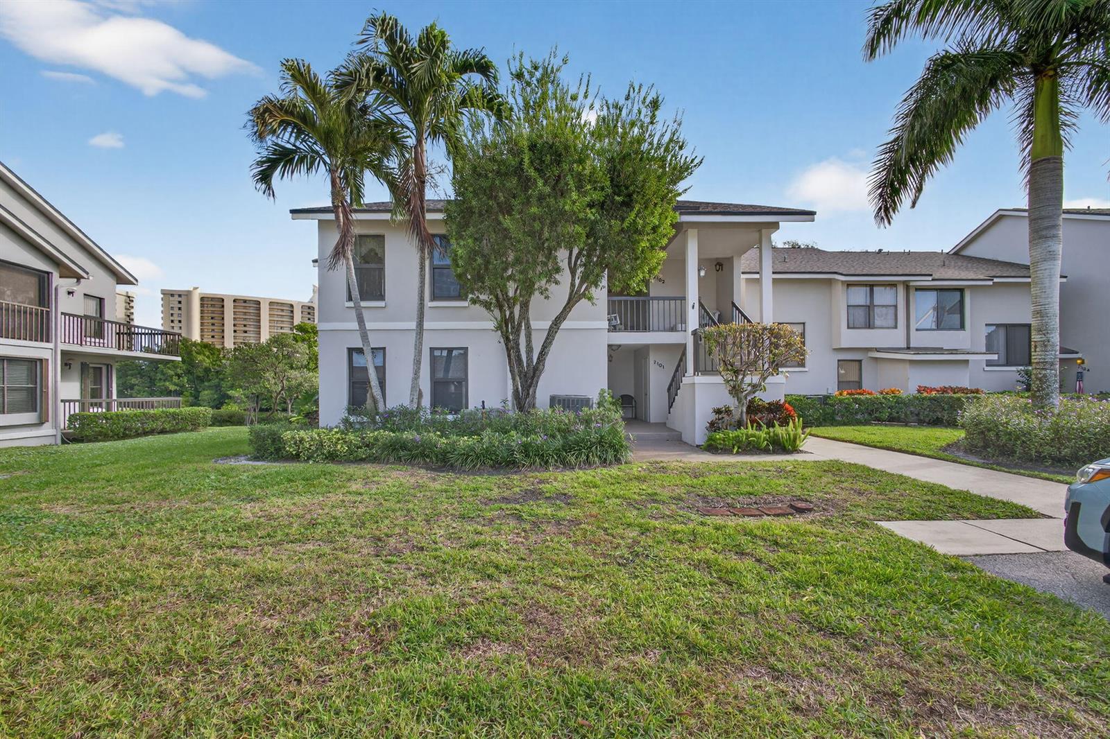 A two-story apartment building with palm trees and a grassy lawn under a blue sky — 2102 Fairway Drive S, Jupiter FL 33477, JUPITER, FL