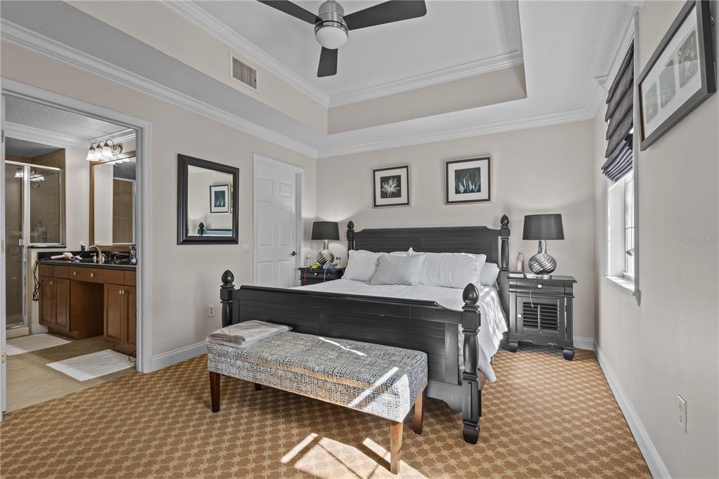A bedroom features a dark wood bed frame, a patterned bench, and an attached bathroom — 7509 MOURNING DOVE CIRCLE UNIT 304, REUNION, FL