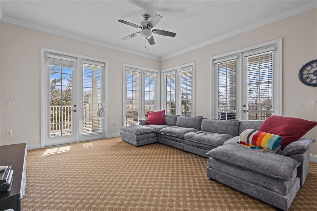 A living room features a large gray sectional sofa, patterned carpet, and multiple glass doors — 7509 MOURNING DOVE CIRCLE UNIT 304, REUNION, FL